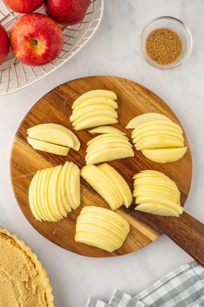 The sliced apples on a wooden cutting board. 