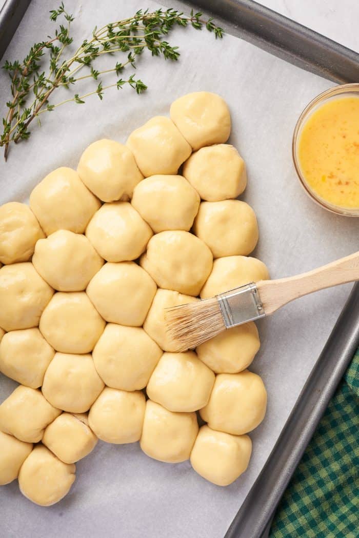 Brushing the dough balls with melted butter.