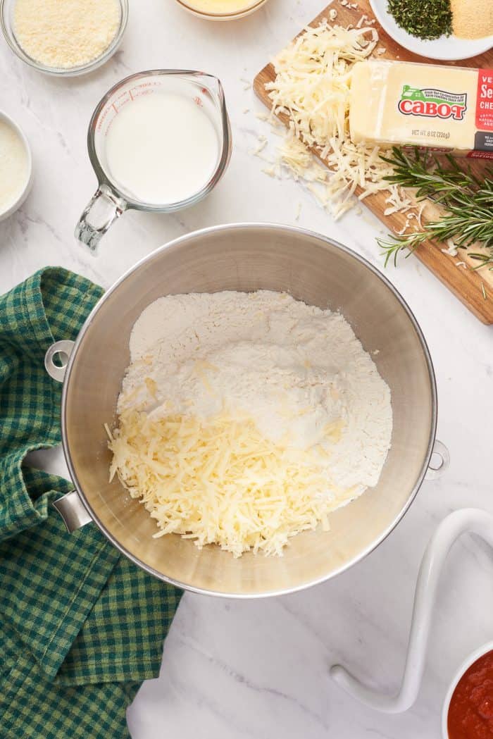A mixing bowl of flour with shredded cheese.