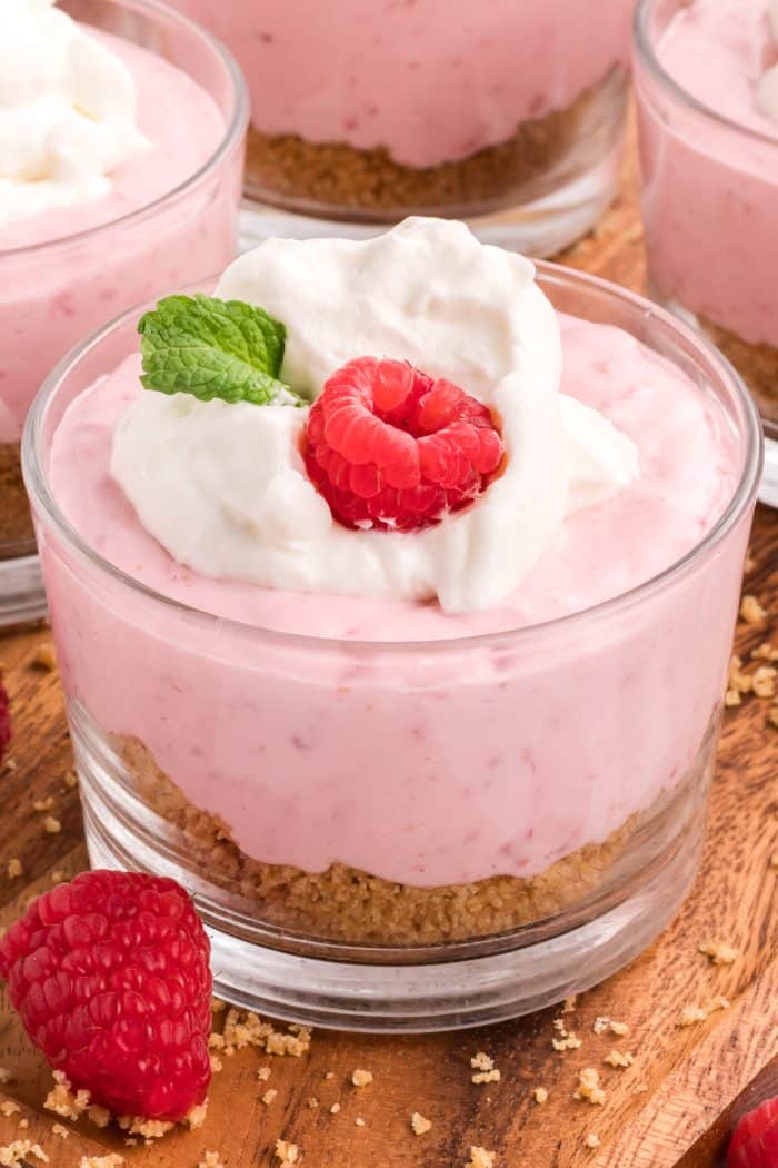 A glass serving dish with raspberry mousse and a spoon.