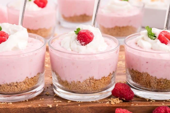 Three serving dishes of raspberry mousse with spoons inserted. 