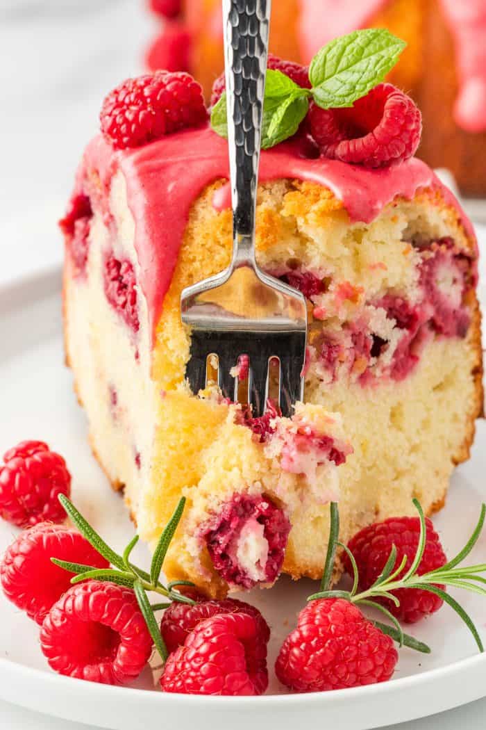 A slice of lemon raspberry bundt cake with a fork pushing through it to take a bite.