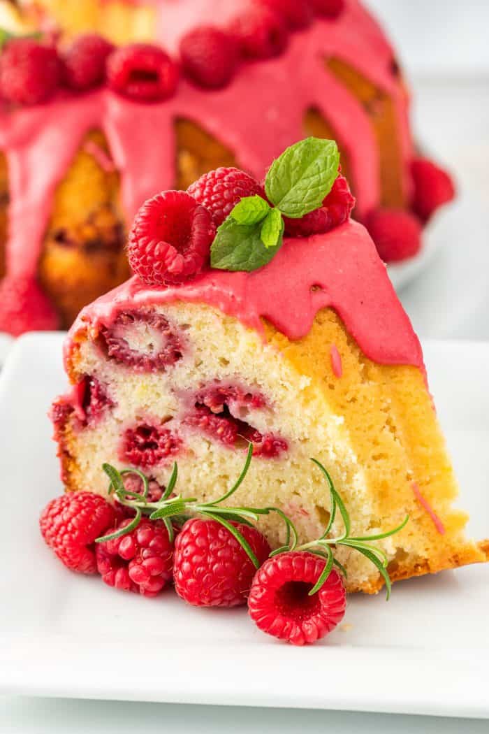 A slice of lemon raspberry bundt cake on a white plate with raspberries.