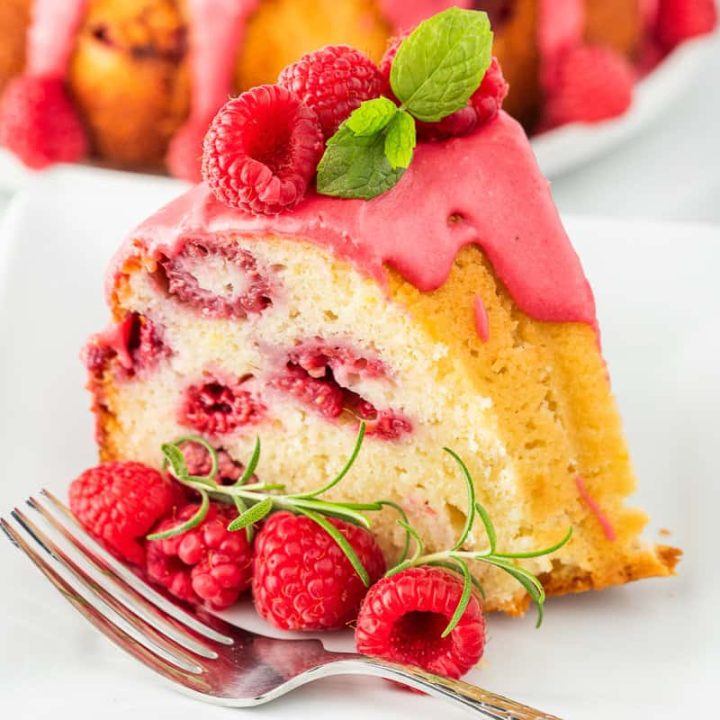 A slice of lemon raspberry bundt cake on a white plate with a fork.