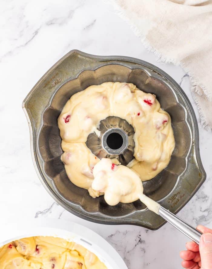 Cake batter being spooned into a Bundt cake pan. 
