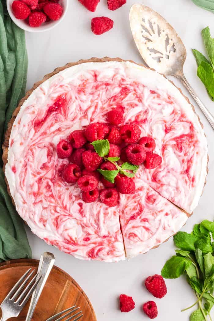An overview of the cheesecake with fresh raspberries and mint leaves.