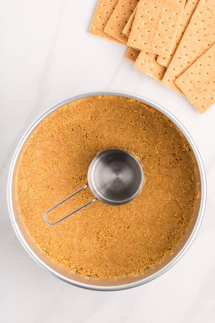 The graham cracker crumbs pressed into the cheesecake pan with a measuring cup. 