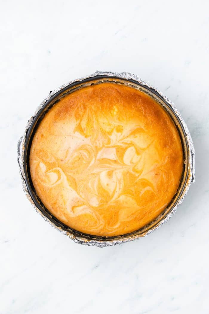 A baked pumpkin swirl cheesecake still in the cheesecake pan.