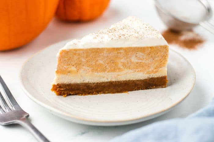 A closeup of a slice of pumpkin swirl cheesecake on a white plate.