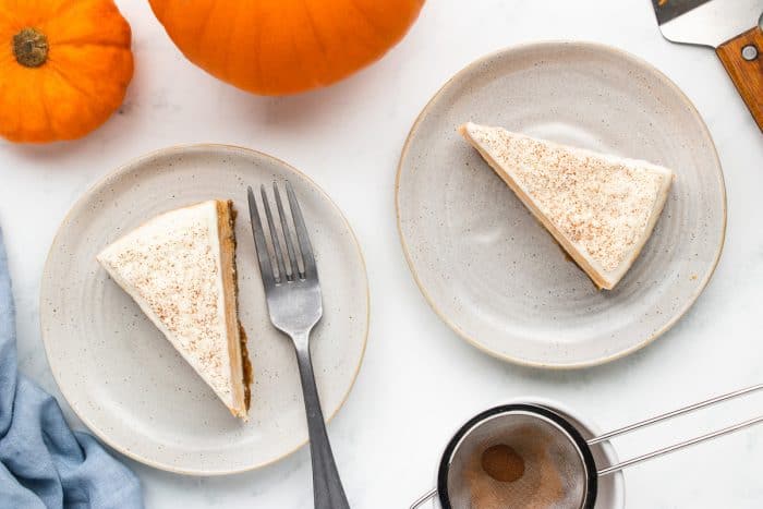 Two slices of pumpkin cheesecake on white plates.