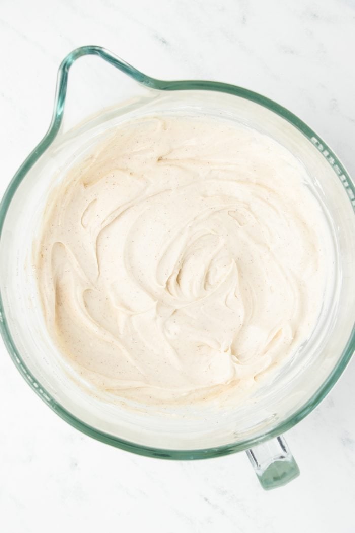 A mixing bowl with cream cheese, sugar, and pumpkin spice added to it.