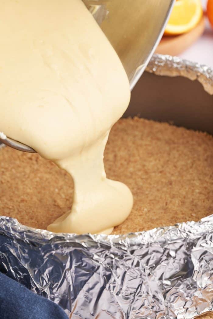 Pouring the cheesecake batter into the baked crust in the cheesecake pan.