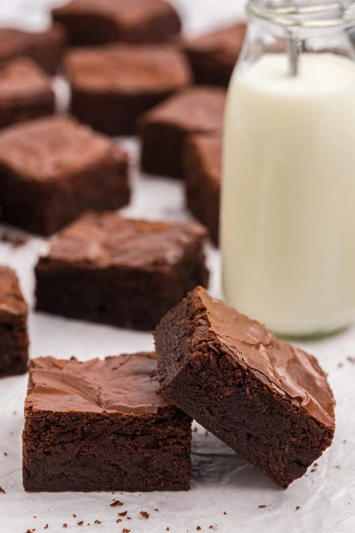 A stack of brownies with a bottle of milk.