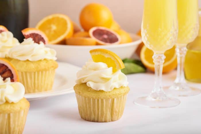 A closeup of mimosa cupcakes with slices of oranges. 