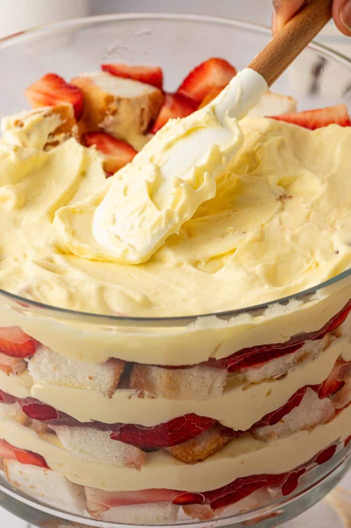 A closeup of the trifle with a knife spreading pudding on it.