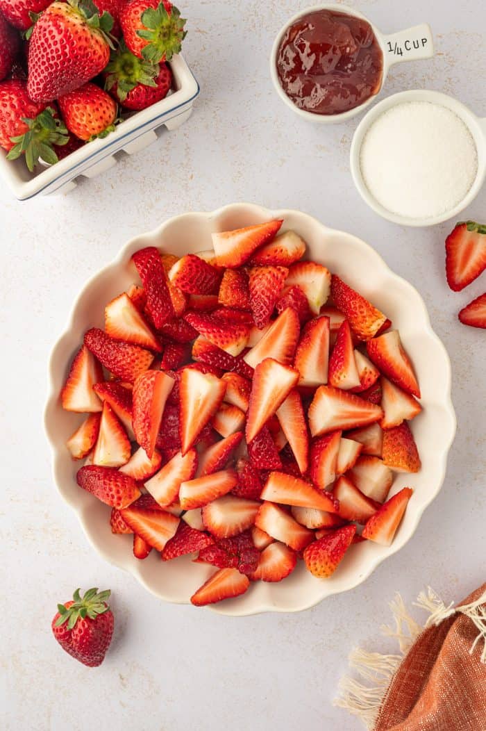 A white bowl of sliced and washed strawberries. 