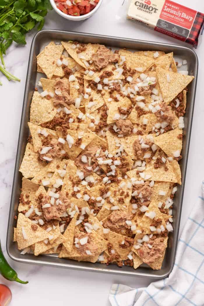 Tortilla chips with a layer of ground beef, refried beans, and onions.