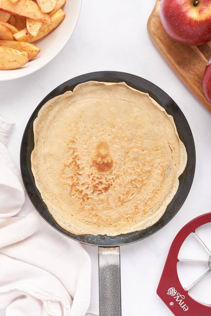 A crepe pan with a cooked crepe on it.