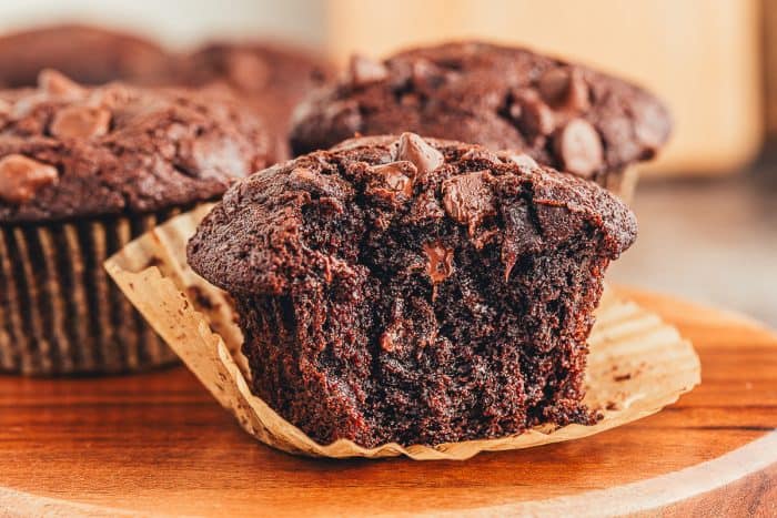 A close up of a double chocolate muffin with a bite taken out of it. 