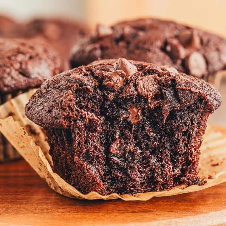 A close up of a double chocolate muffin with a bite taken out of it.