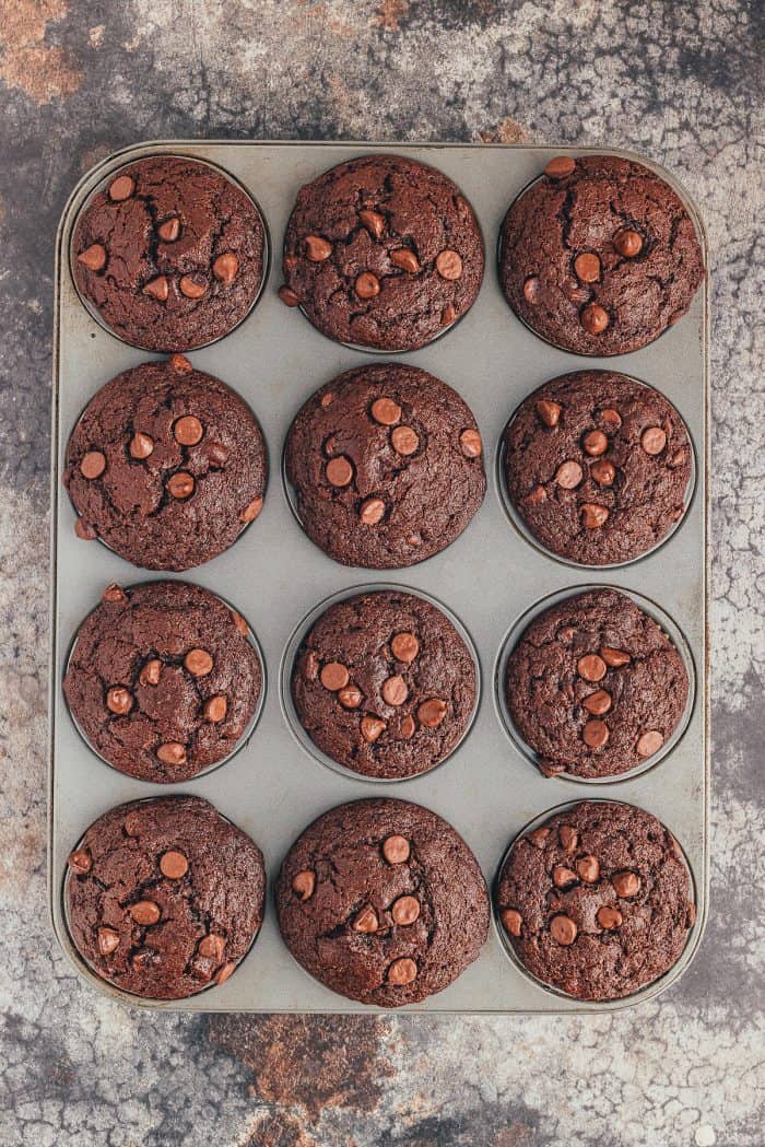 A muffin pan filled with baked double chocolate muffins.