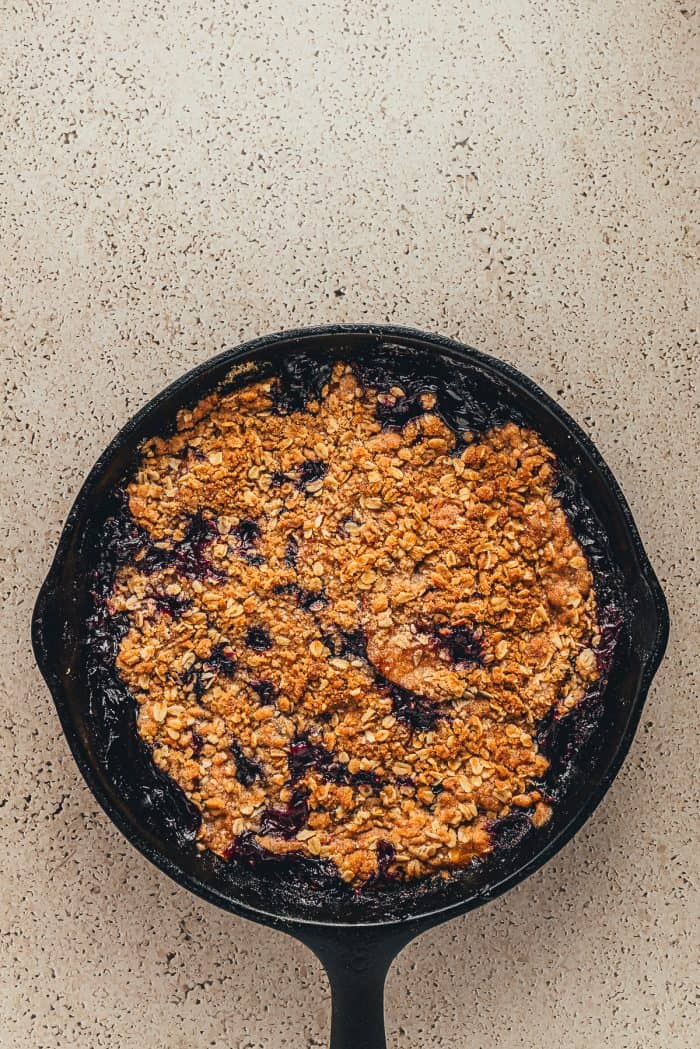 A cast-iron skillet with baked blueberry peach crumble.