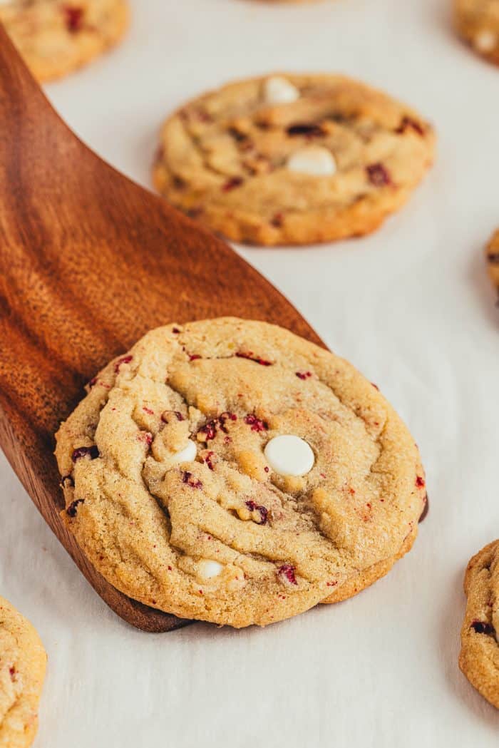 A white chocolate raspberry cookie on a wooden spatula.