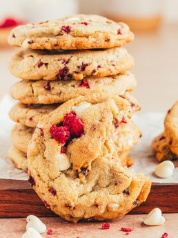 A stack of white chocolate raspberry cookies with a bite taken out of one cookie.
