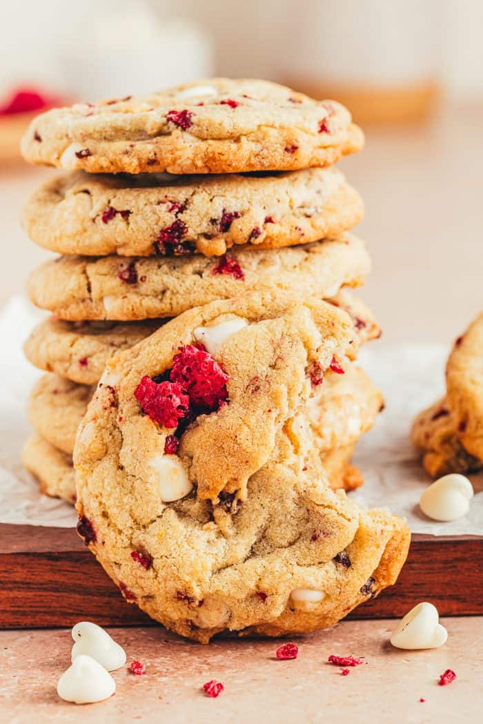 A stack of white chocolate raspberry cookies with a bite taken out of one cookie.