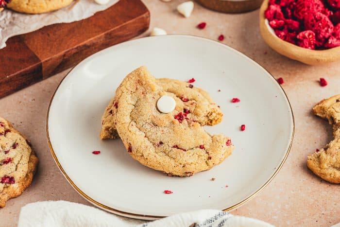 A plate with a raspberry white chocolate cookie broken in half.