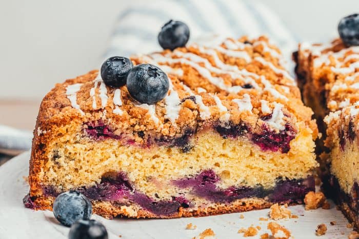 A slice of blueberry sour cream coffee cake on a white plate.