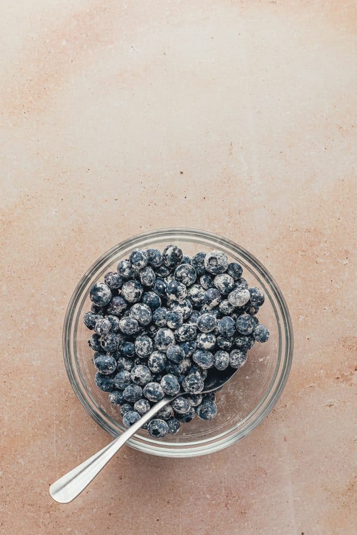 A bowl with fresh blueberries and a spoon.