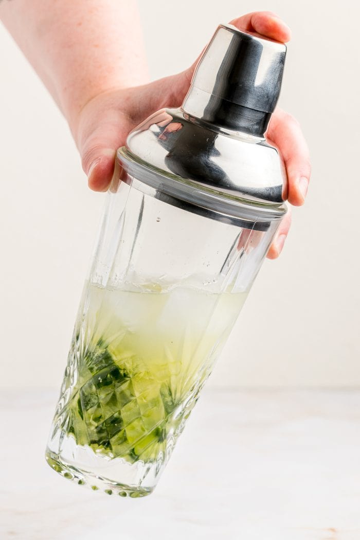 A cucumber Basil gimlet being shaken in a cocktail shaker. 