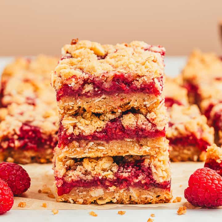 A stack of three raspberry crumble bars with more bars behind it.