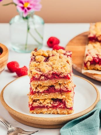 A stack of three raspberry crumble bars on a white plate.