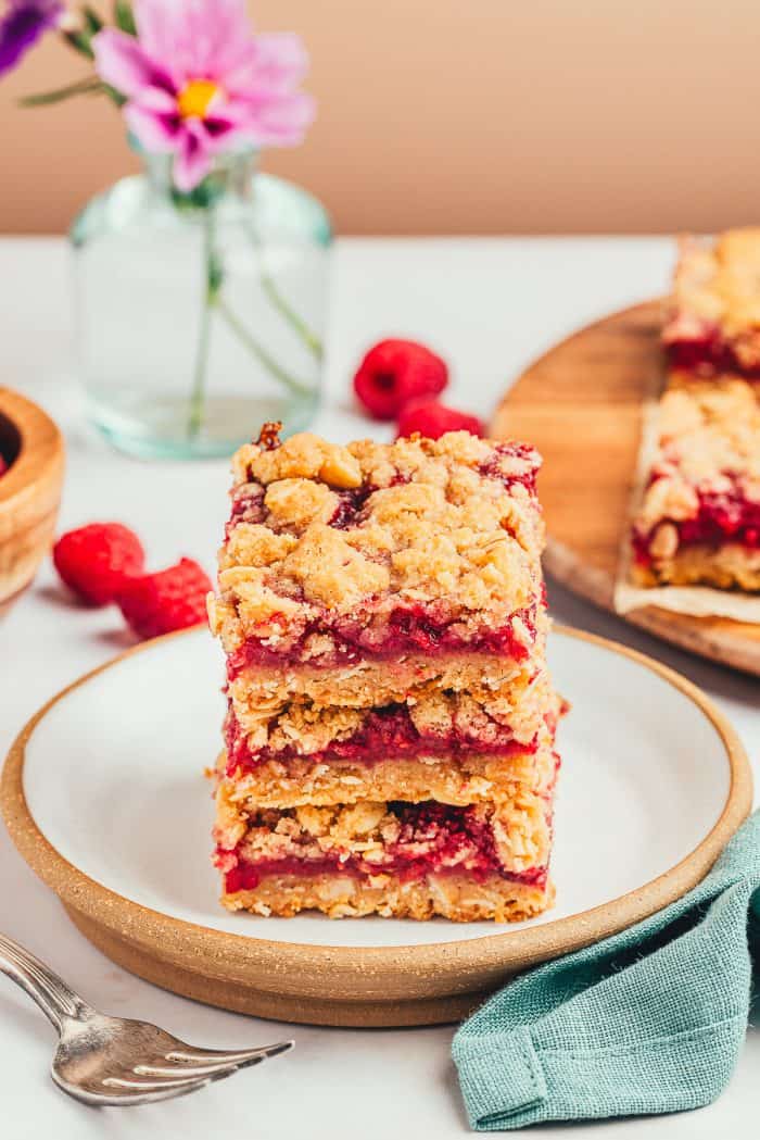 A stack of three raspberry crumble bars on a white plate.