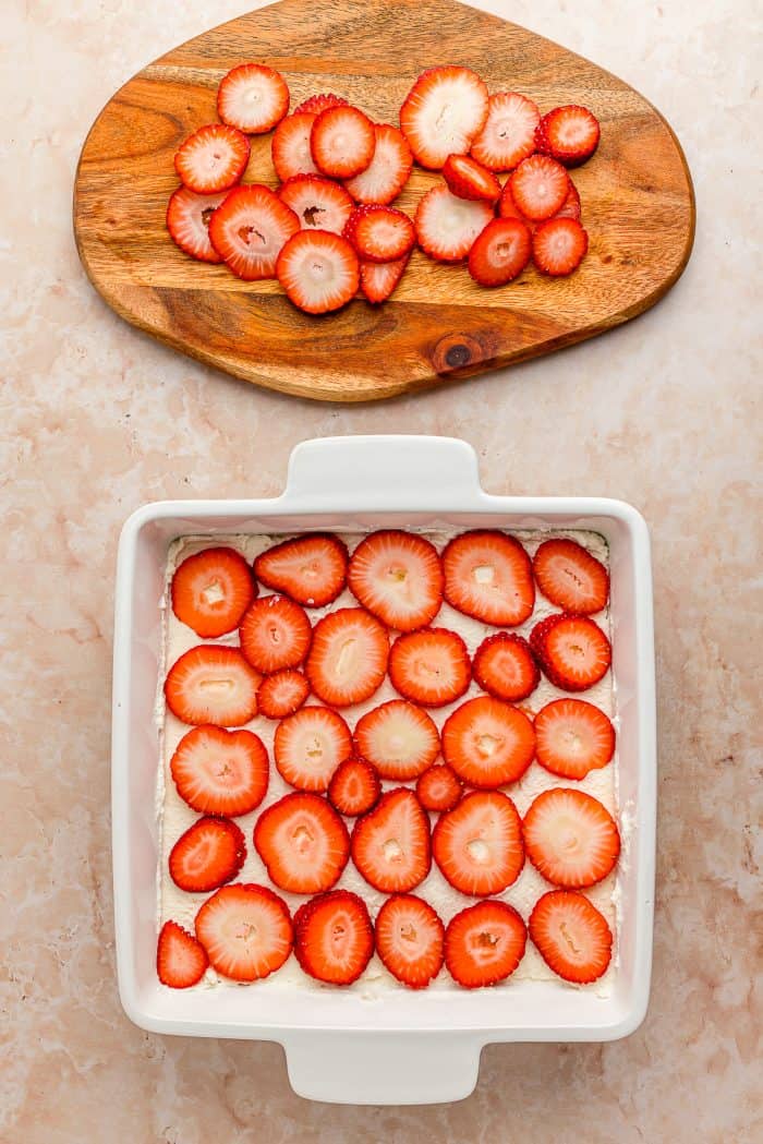 A white baking tray with a layer of sliced strawberries.