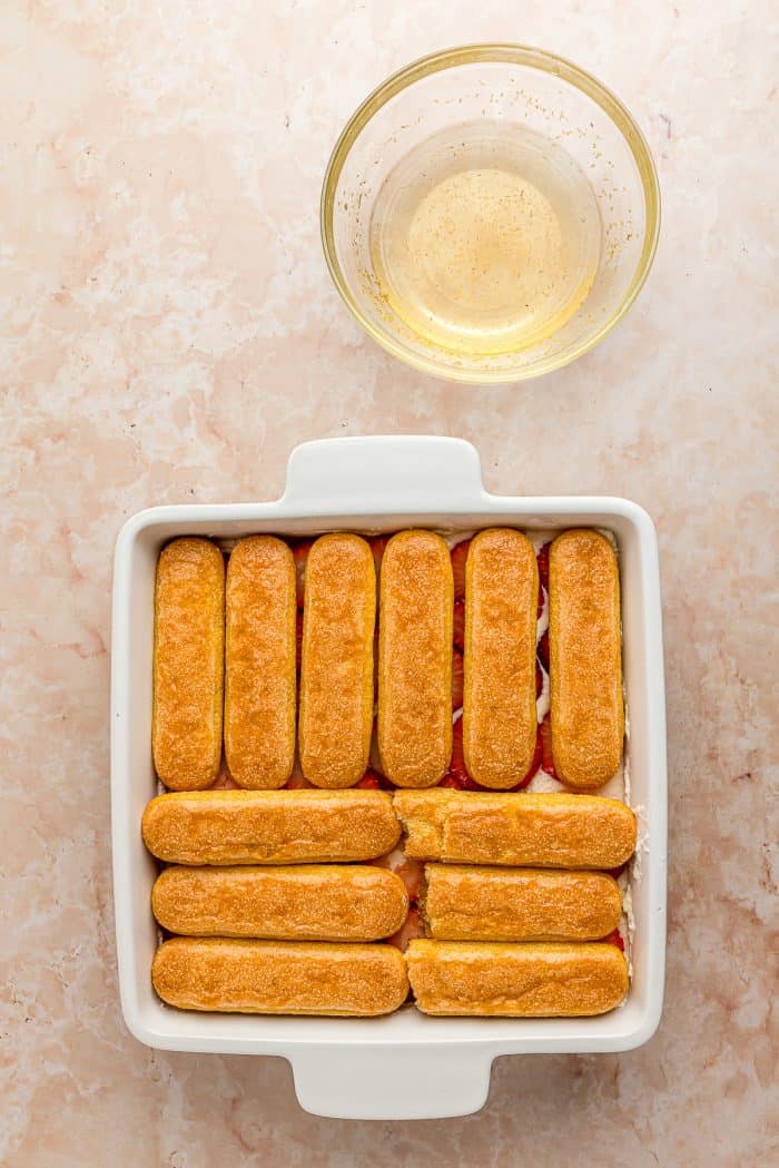 A white baking tray with a layer of lady fingers.