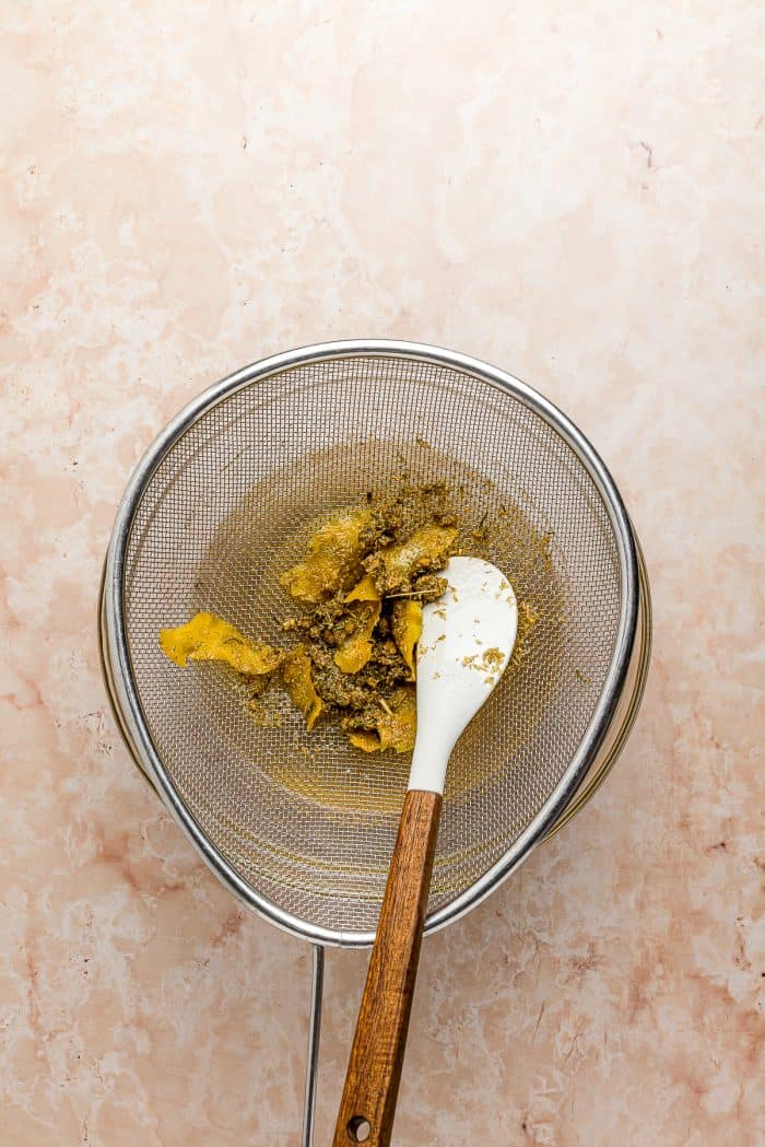 A bowl with simple syrup, lemon rind, and dried chamomile.
