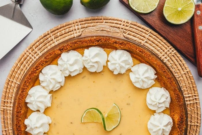 A key lime pie with sliced key limes in the background.
