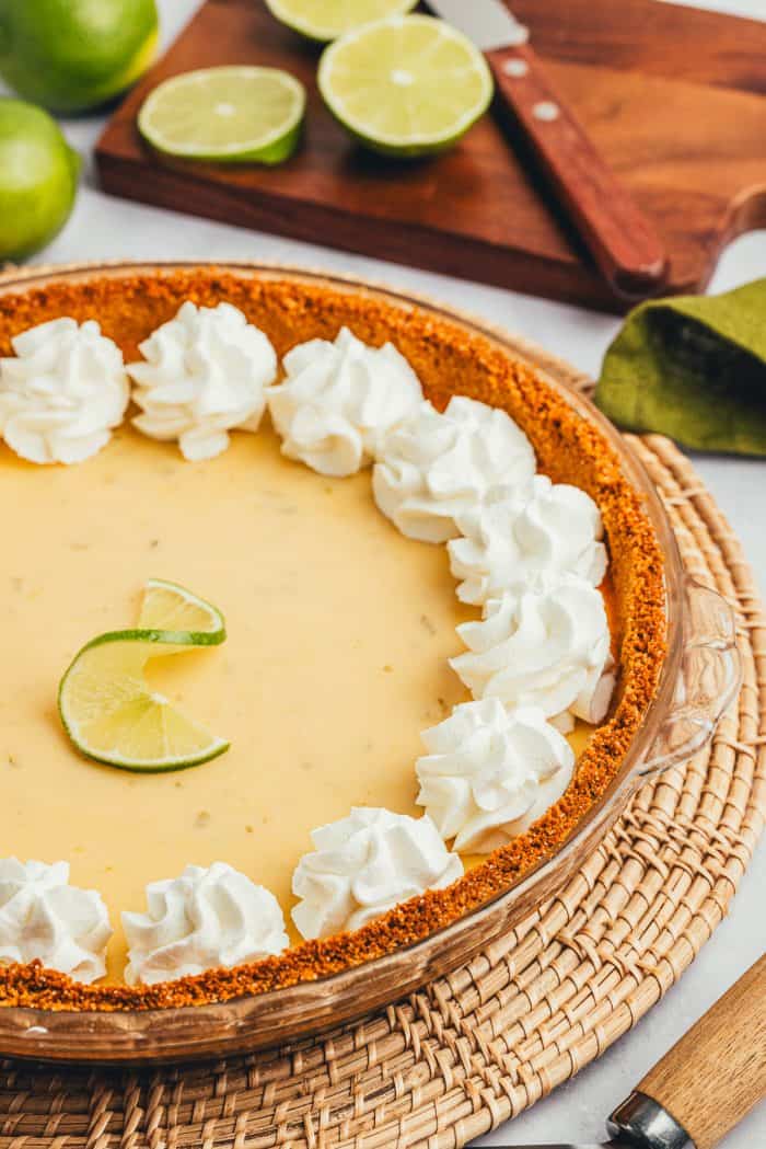 A key lime pie with sliced key limes in the background.