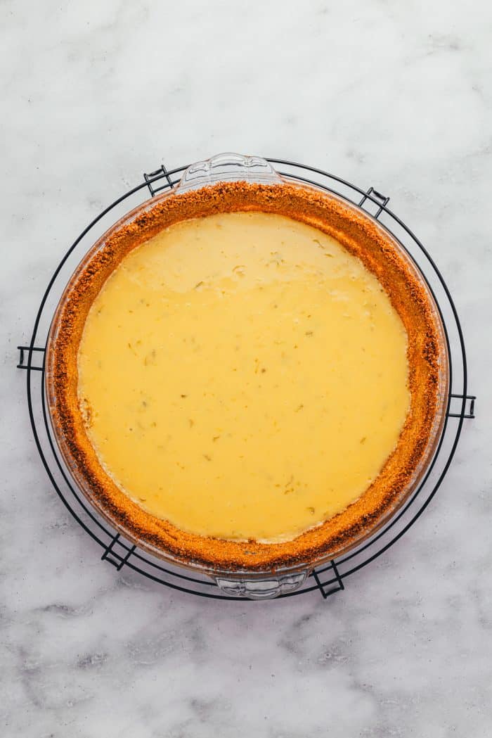 A baked key lime pie on a cooling rack.