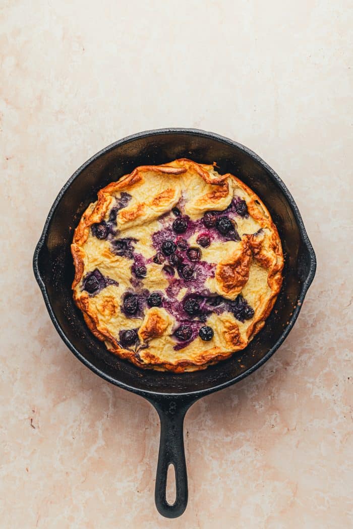 A skillet with a baked blueberry lemon Dutch pancake.