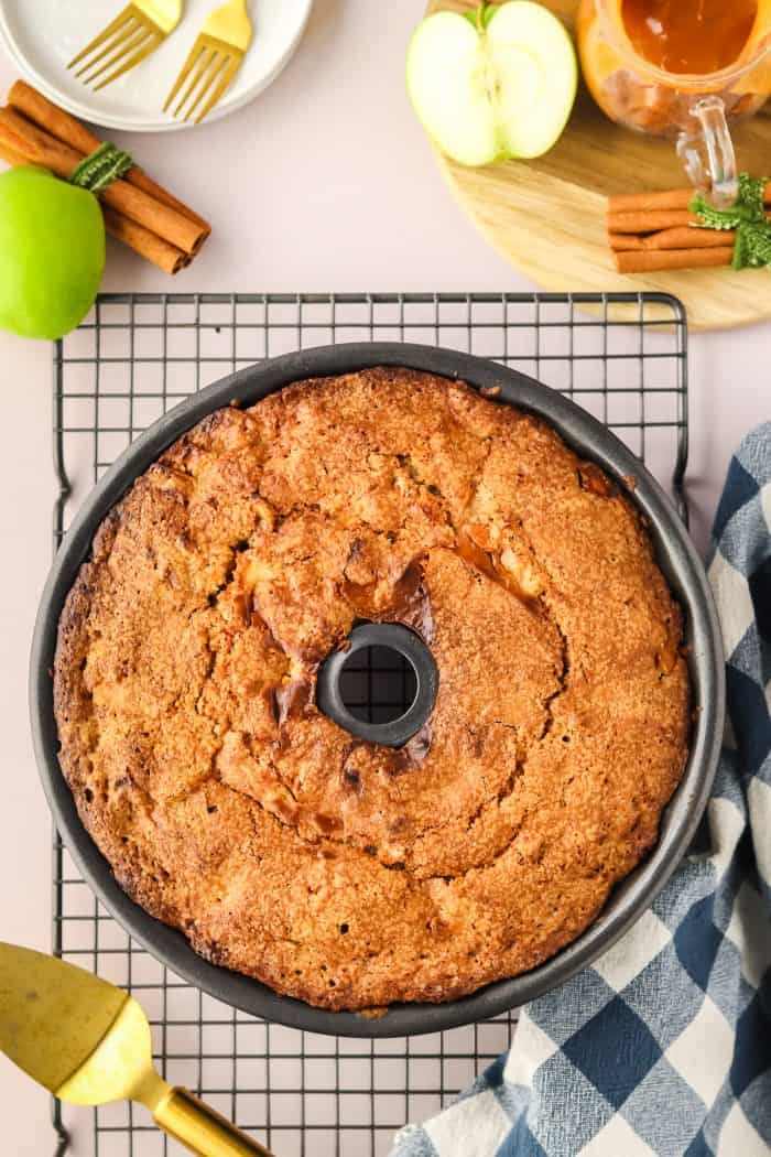 The baked caramel apple Bundt cake in a Bundt pan cooling on a cooling rake.