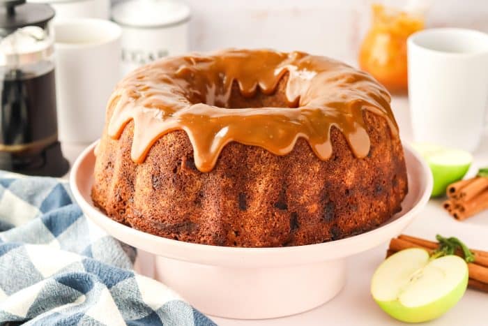 An image showing the whole caramel apple Bundt cake on a white cake stand.