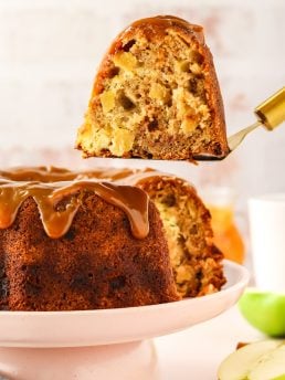 An image of a slice of caramel apple Bundt cake on a cake lifter being removed from the whole cake.