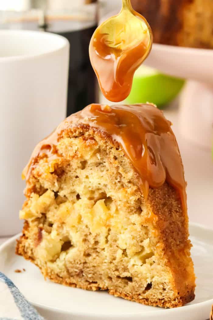 A slice of apple Bundt cake with caramel sauce being poured over it.