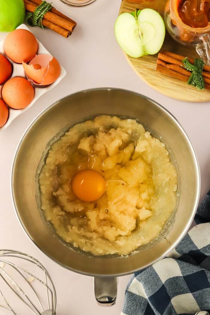 An egg mixed with cake batter in a metal bowl.