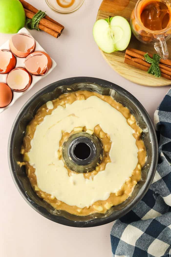 The cake batter with a layer of cream cheese in a Bundt pan.