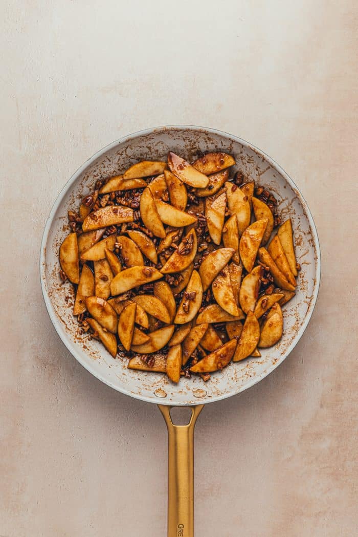 Cooked sliced green apples in a skillet.